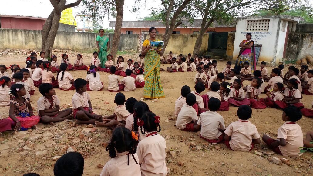 Students gather around as a teacher reads from a Hygiene with Chhota Bheem storybook.