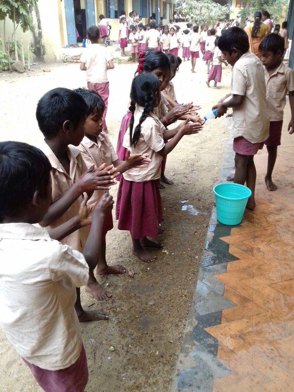 Children help each other wash their hands using soapy bottles made through their experience with the program.
