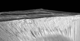 Dark narrow streaks called recurring slope lineae emanating out of the walls of Garni crater on Mars. The dark streaks here are up to a few hundred meters in length. They are hypothesized to be formed by the flow of briny liquid water on Mars. Vertical exaggeration is 1.5. (Photo courtesy of NASA/JPL/University of Arizona.)