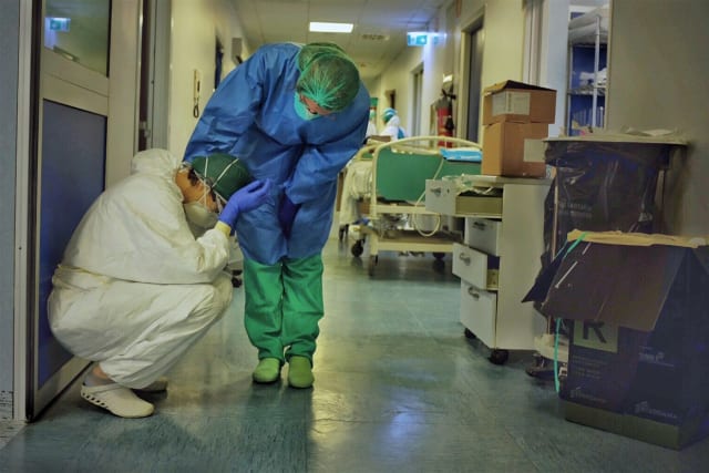 Two intensive care professionals comfort each other at an Italian hospital. (Image courtesy of Paolo Miranda.)