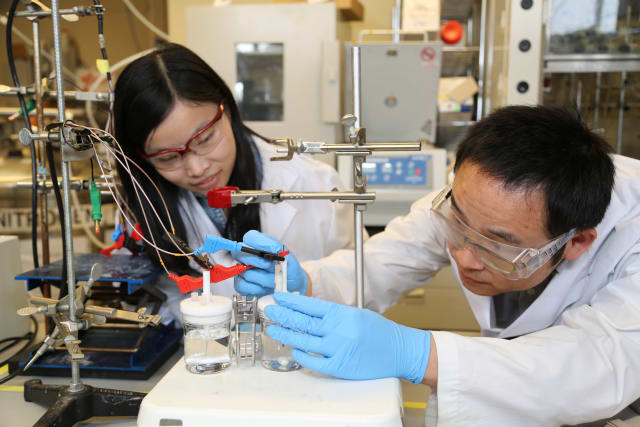 Researchers Xueli Zheng, left, and Bo Zhang test a previous catalyst for the artificial photosynthesis system. The new catalyst works at lower pH, leading to an improvement in the overall efficiency of the system. (Image courtesy of Marit Mitchell.)