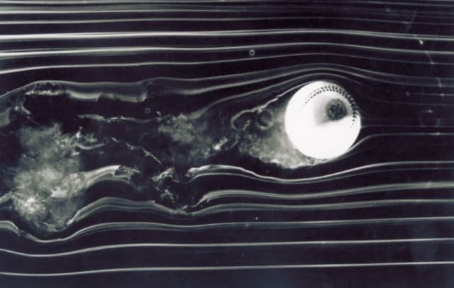 An early image of a baseball spinning through a wind tunnel. In this image, the baseball is spinning counterclockwise, producing less pressure on the top of the ball and more on the bottom. If this were a side view, the resulting Magnus force would make the baseball rise. (Source: University of Notre Dame.)