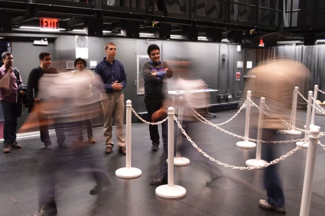 Jonathan Boreyko (left) and graduate student Farzad Ahmadi monitor pedestrian spacing as a line empties at The Cube in Virginia Tech's Moss Arts Center. The team found that people move slowly but accelerate quickly, meaning packing tightly in lines increases pedestrians' chances of moving through faster. (Image courtesy of Virginia Tech.)