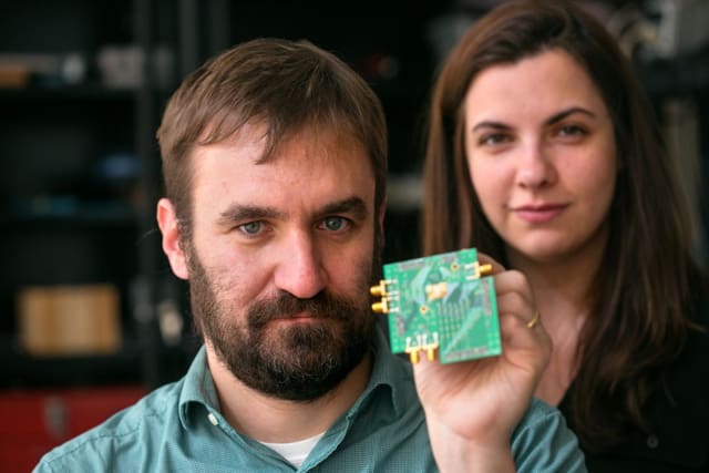 Al Molnar, holding a test board with the two-way transceiver chip mounted in the center, is shown with graduate student Hazal Yüksel in Molnar's lab. (Image courtesy of Cornell University.)