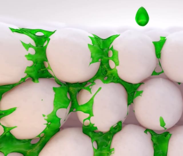 Liquid binder (shown in green) is used to lock powder particles in place. With additional nanoparticles in the binder, some of the interstices between powder particles can be filled to increase part density. (Image courtesy of ExOne.)