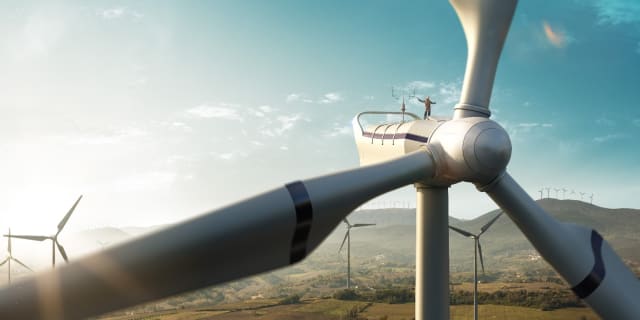Green energy galore, but what of the energy used to create these massive machines? Look closely to see the human on top. (Stock photo)