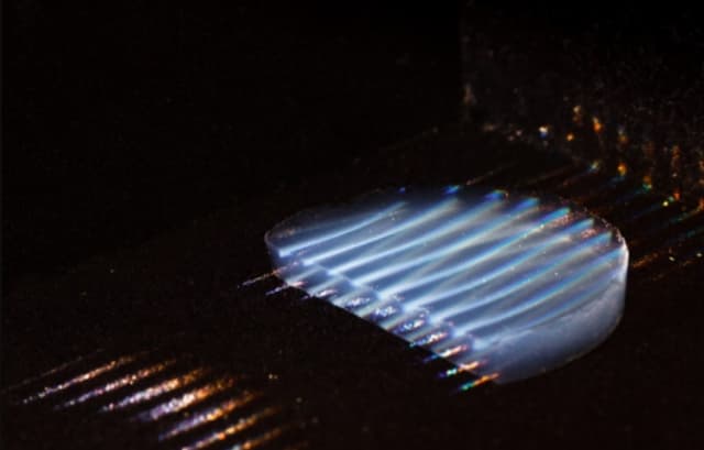 A new transparent aerogel insulating material, made visible in the photo using parallel laser beams, transmits 95 percent of sunlight. Researchers spent four years developing the silica-based material. (Image courtesy of MIT.)