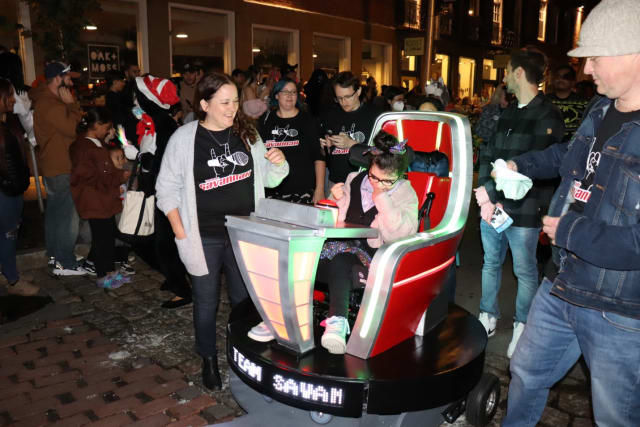 Riding in style. Savannah Smith, with her parents and Team Savannah members (Magic Wheelchair volunteers and Dassault Systèmes SOLIDWORKS employees), rides in a Salem, Mass. Halloween parade on a custom wheelchair inspired by The Voice, her favorite show. (Picture courtesy of Dassault Systèmes.)