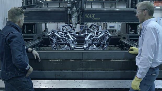 McCoy (left) and Gardner (right) inspect Hackrod’s proprietary AM process, which is controlled by a Siemens SINUMERIK840D and 3D prints polymer and aluminum by two techniques: the polymer is printed through extrusion, and the aluminum is printed using a wire arc process. These two methods of industrial AM are paired with 5-axis CNC machining and rest on one platform’s Z-axis. (Image courtesy of Hackrod.)