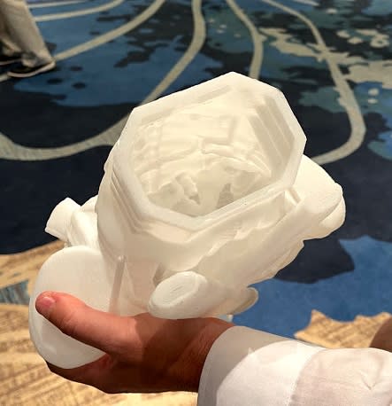 Massivit 3D's software has the 3D printer deposit extra material where support is needed. The extra material is visible as lumps on the inside of this hollow 3D-printed part on display at AMUG 2021.