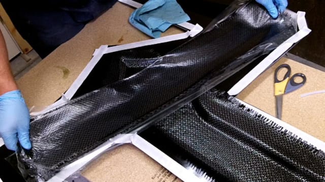 Pieces of carbon fiber being laid into a mold that will be filled with epoxy resin and vacuum sealed. (Image courtesy of The Project Junkie.)