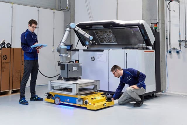 Associates demonstrate automation work with a robotic arm and a HP Multi Jet Fusion system at the Additive Manufacturing Campus. (Image courtesy of the BMW Group.)