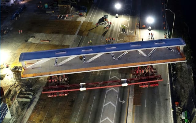 Accelerated bridge construction (ABC) techniques used for the FIU bridge. The prefabricated main section main span (which was later to collapse) was fabricated nearby and is shown here being moved into place in a five-hour overnight operation while SW 8th St was closed to traffic. (Image courtesy of Miami Herald.)