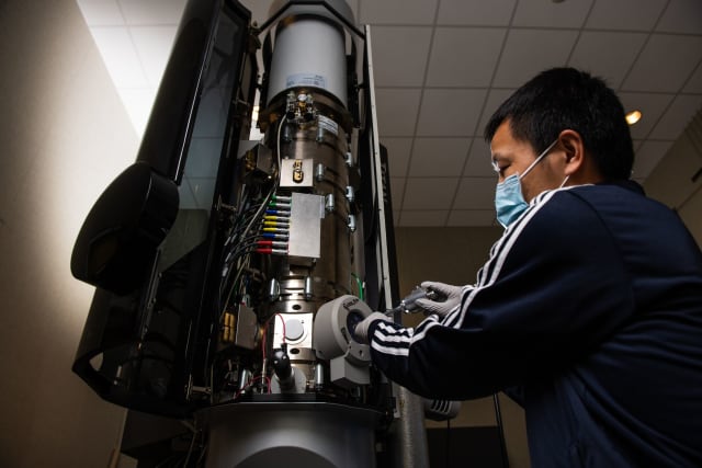 The research team used a transmission electron microscope to record the molecular action inside a lithium-ion battery as it charged and discharged. Here, PNNL scientist Yaobin Xu adjusts a sample. (Photo by Andrea Starr | Pacific Northwest National Laboratory.)
