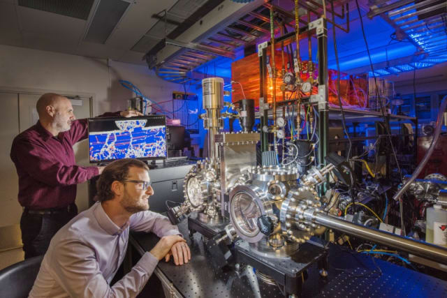 Sandia National Laboratories researchers Michael Chandross, left, and Nic Argibay show a computer simulation used to predict the unprecedented wear resistance of their platinum-gold alloy, and an environmental tribometer used to demonstrate it. (Photo by Randy Montoya.)