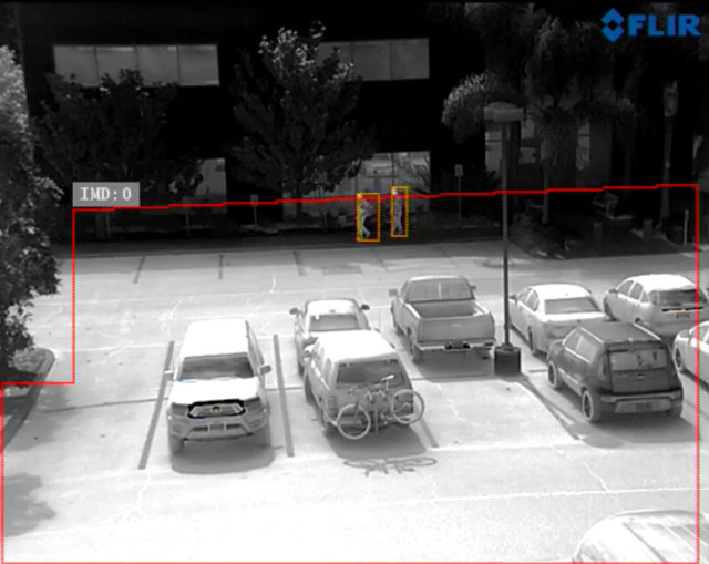 An infrared security camera identifies two people in a parking lot. (Image courtesy of FLIR.)
