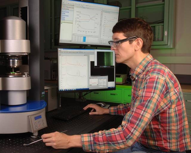 NIST researcher Anthony Kotula using the new rheo-Raman microscope, a three-in-one instrument that enables researchers to measure the flow properties of a material along with its microscopic structure and composition. (Image courtesy of D. Anderson/NIST.)