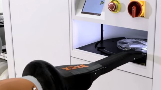 The KMR iiwa makes contact with the edge of a slot within a SIPLACE Material Tower, feeling around for the component wheel it has been ordered to retrieve.