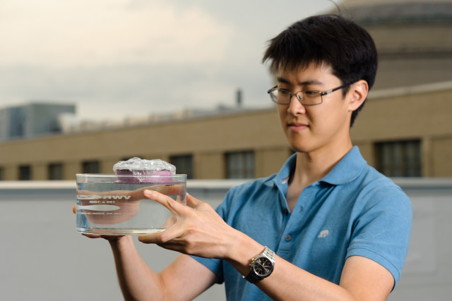 George Ni holds a bubble-wrapped, sponge-like device that soaks up natural sunlight and heats water to boiling temperatures, generating steam through its pores. (Image courtesy of Jeremy Cho.)