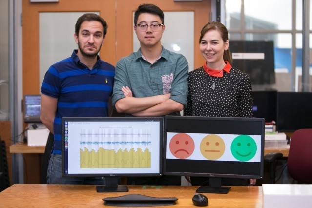 Left to right: PhD student Fadel Adib, PhD student Mingmin Zhao, and Professor Dina Katabi pose with their EQ-Radio device, which can detect emotion using wireless signals. (Image courtesy of Jason Dorfman/MIT CSAIL.)