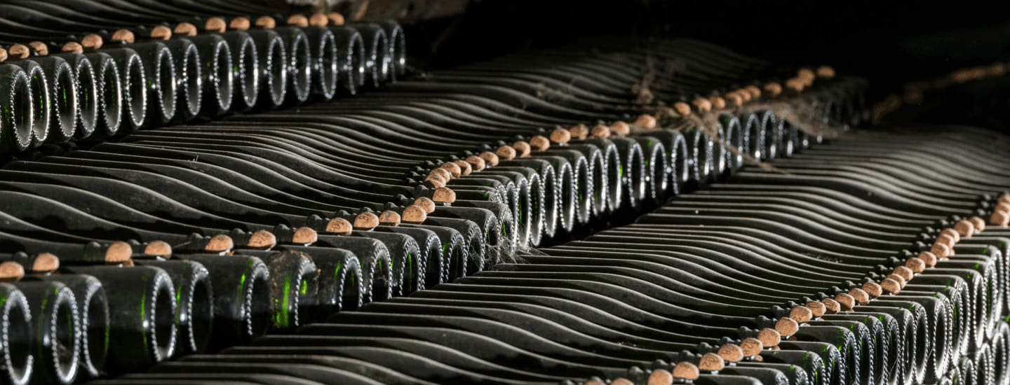 An image of sparkling wine bottles aging in cellar