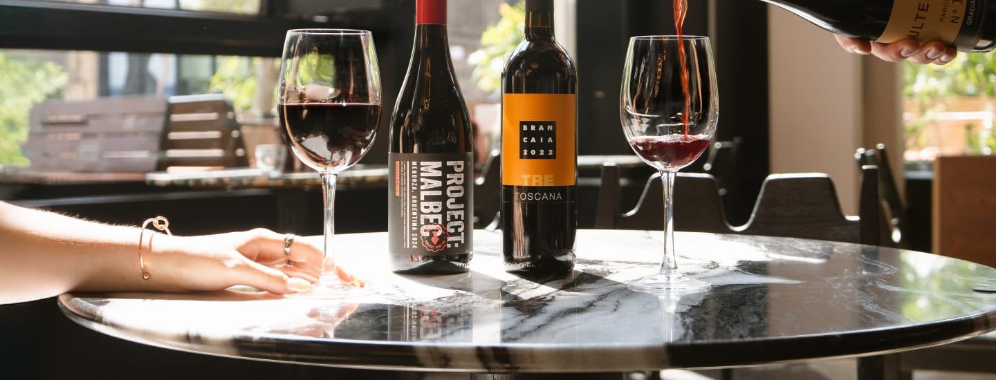 An image of a server pouring a bottle of red wine in a restaurant