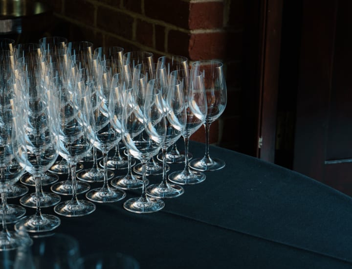 Empty wine glasses on a navy blue table laid out ready for a wine tasting.