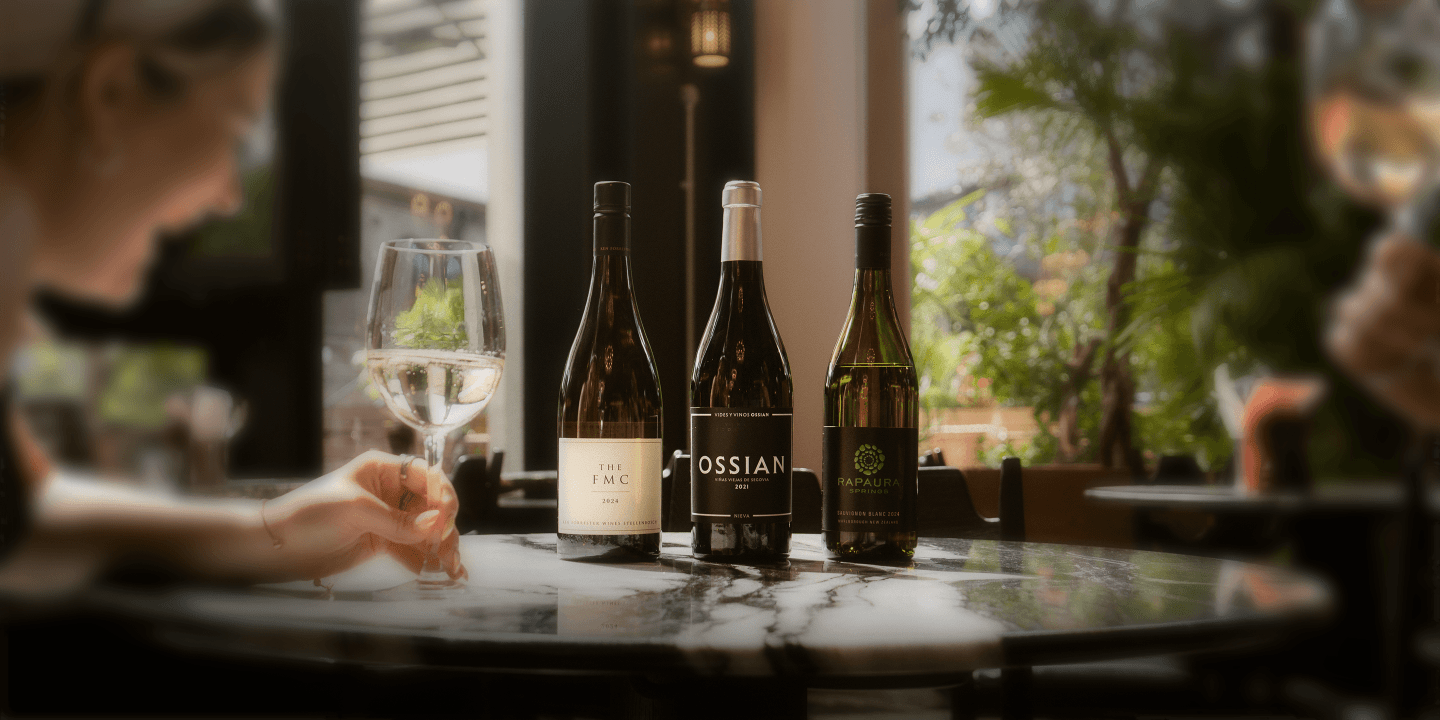 A photo of three bottles of wine lined up on a marble table