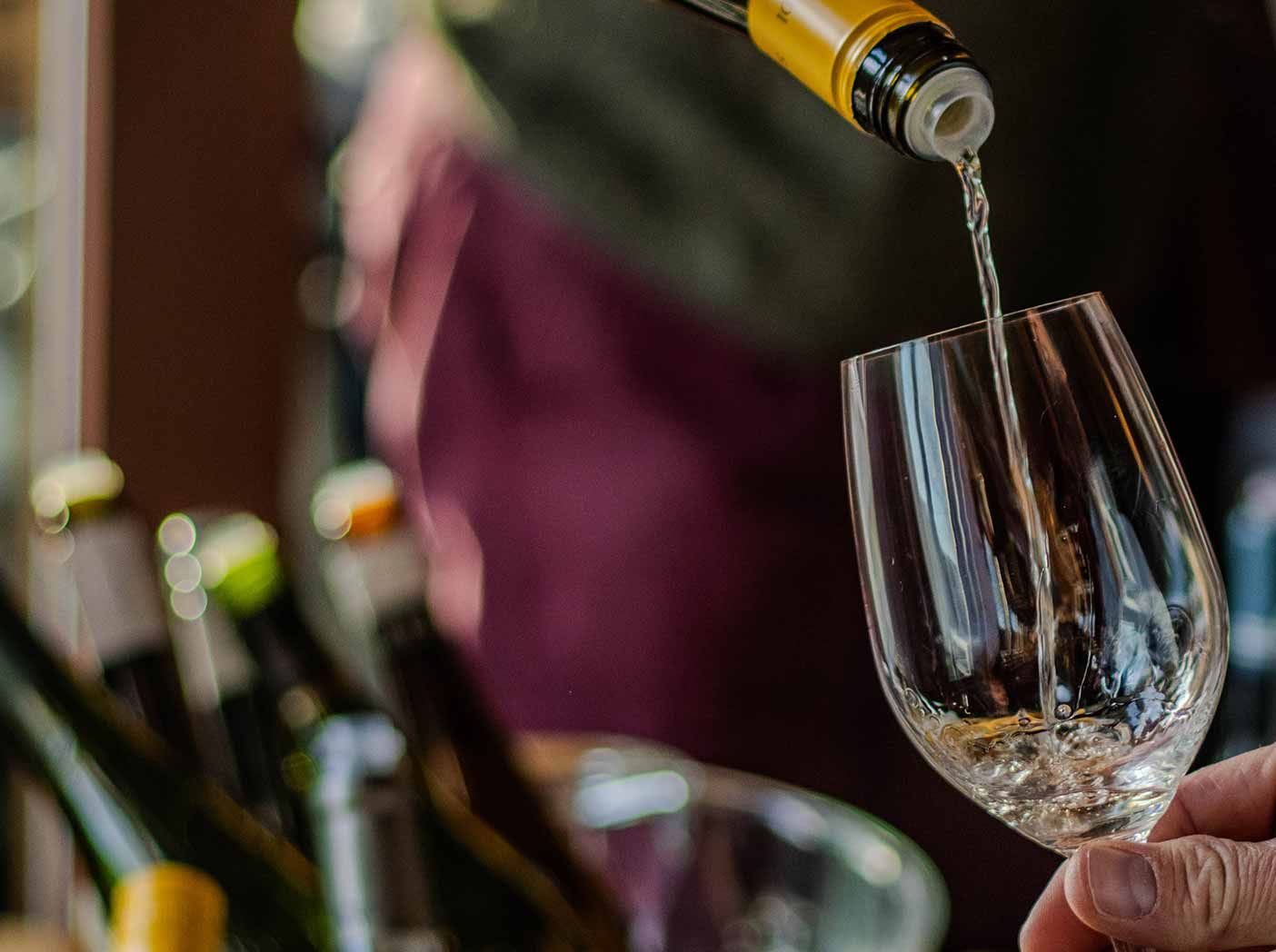 An image of a tasting sample of white wine being poured into a glass at our Great Spring Tasting