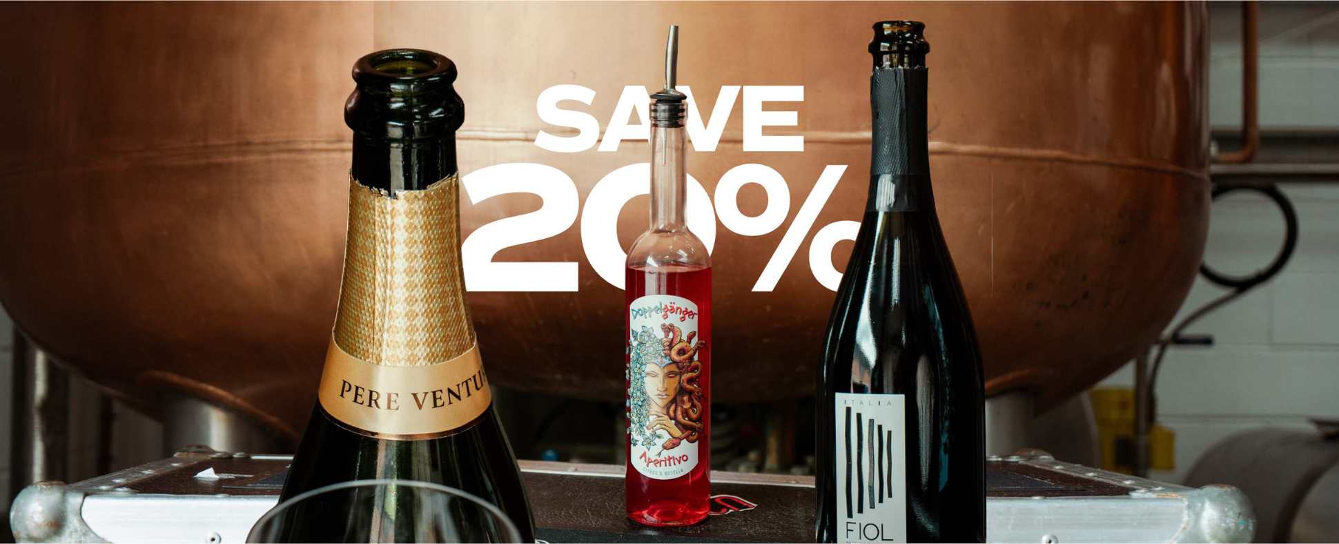 Bottles infront of a copper still - Use code SPRITZKIOSK for 20% off the pair when you buy Doppelgänger Aperitivo with one of our featured sparkling wines