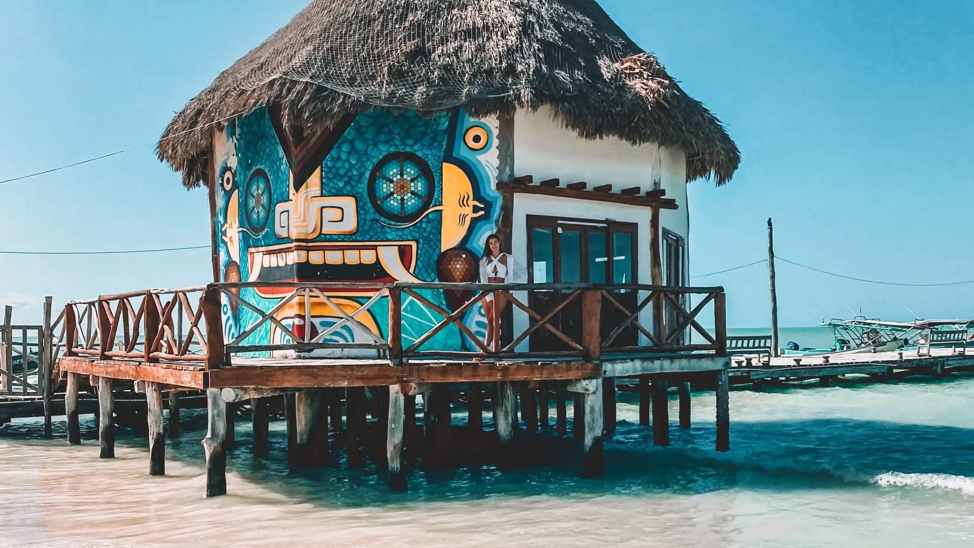 Bunte Strandhütte auf Stelzen im türkisblauen Wasser, Mexiko