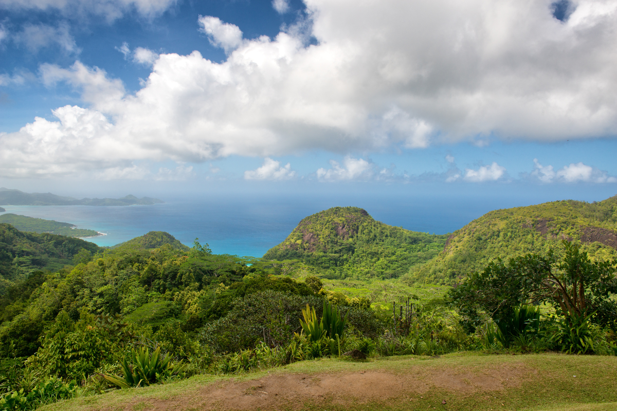 Panoramablick auf grüne Hügel und türkisblaues Meer der Seychellen mit Granitfelsen und üppiger Vegetation