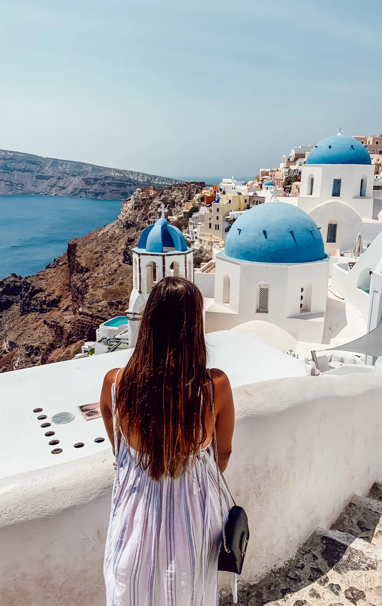 Frau blickt auf blaue Kirchenkuppeln in Oia, Santorini – Griechenland Reise Mittelmeer