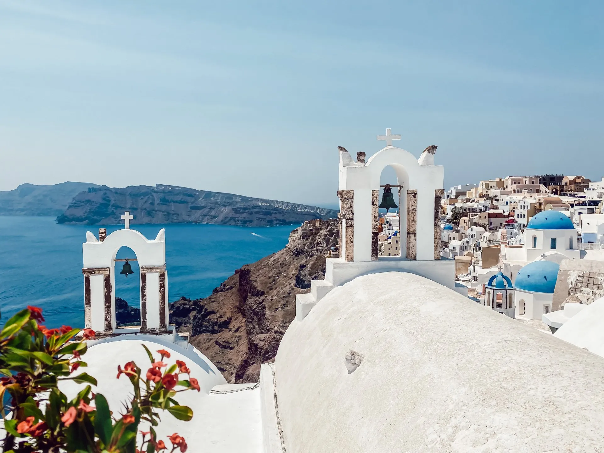 Weiße Kirchen mit blauen Kuppeln in Oia, Santorini, mit Blick auf die Caldera und das Ägäische Meer
