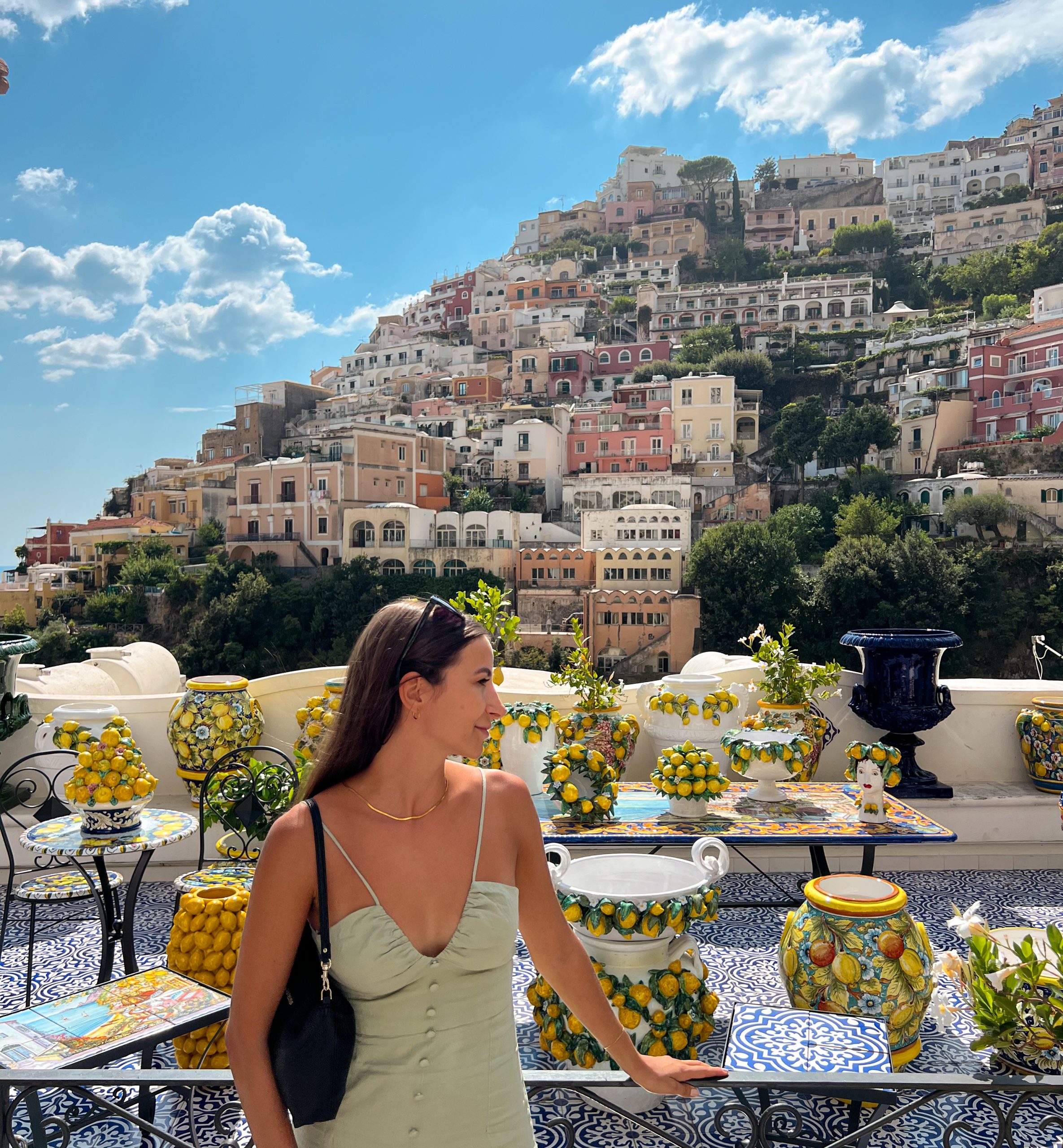 Frau bewundert bunte Keramik in Positano mit malerischer Amalfiküste im Hintergrund, Italien