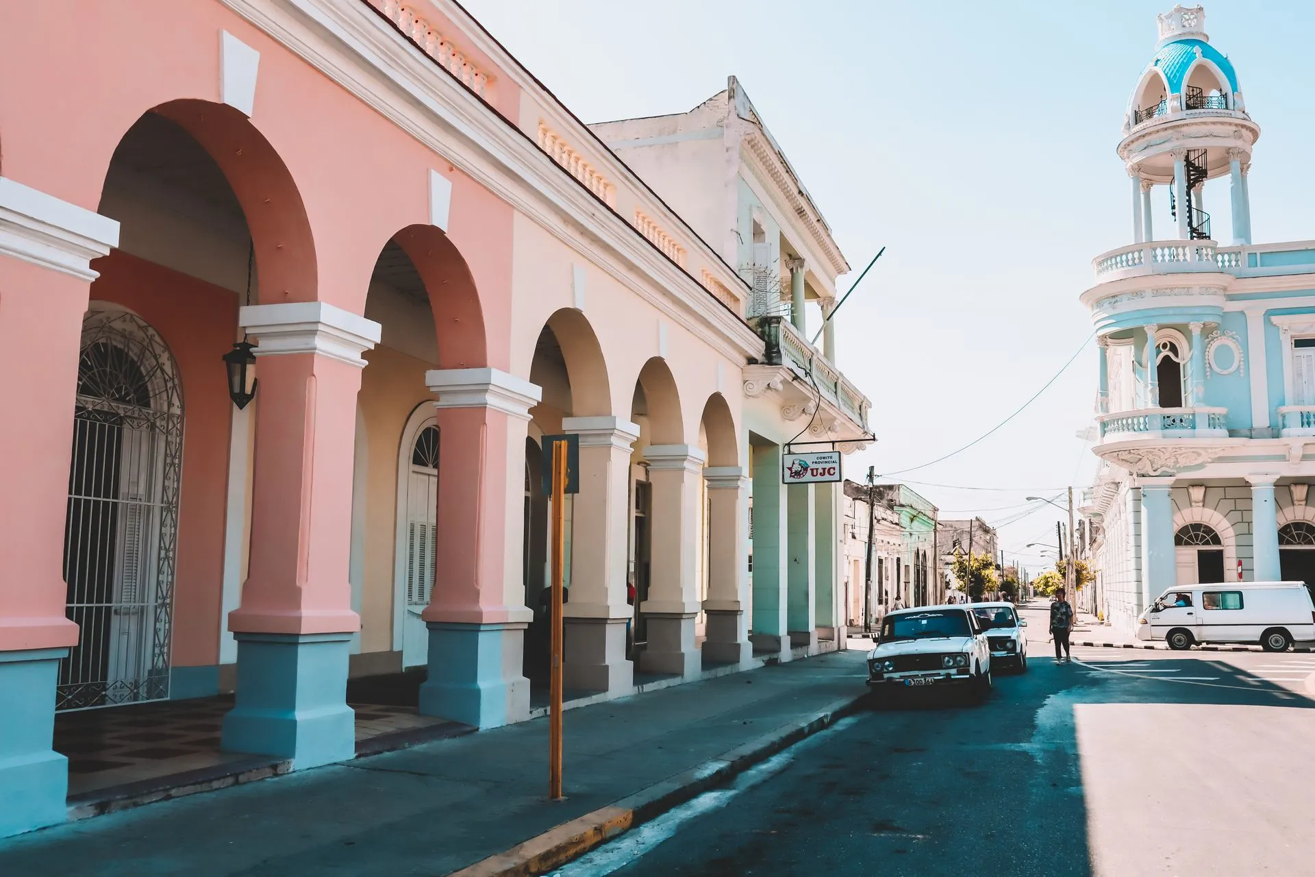 Bunte Kolonialarchitektur in Cienfuegos, Kuba – pastellfarbene Bögen und blauer Turm an sonniger Straße