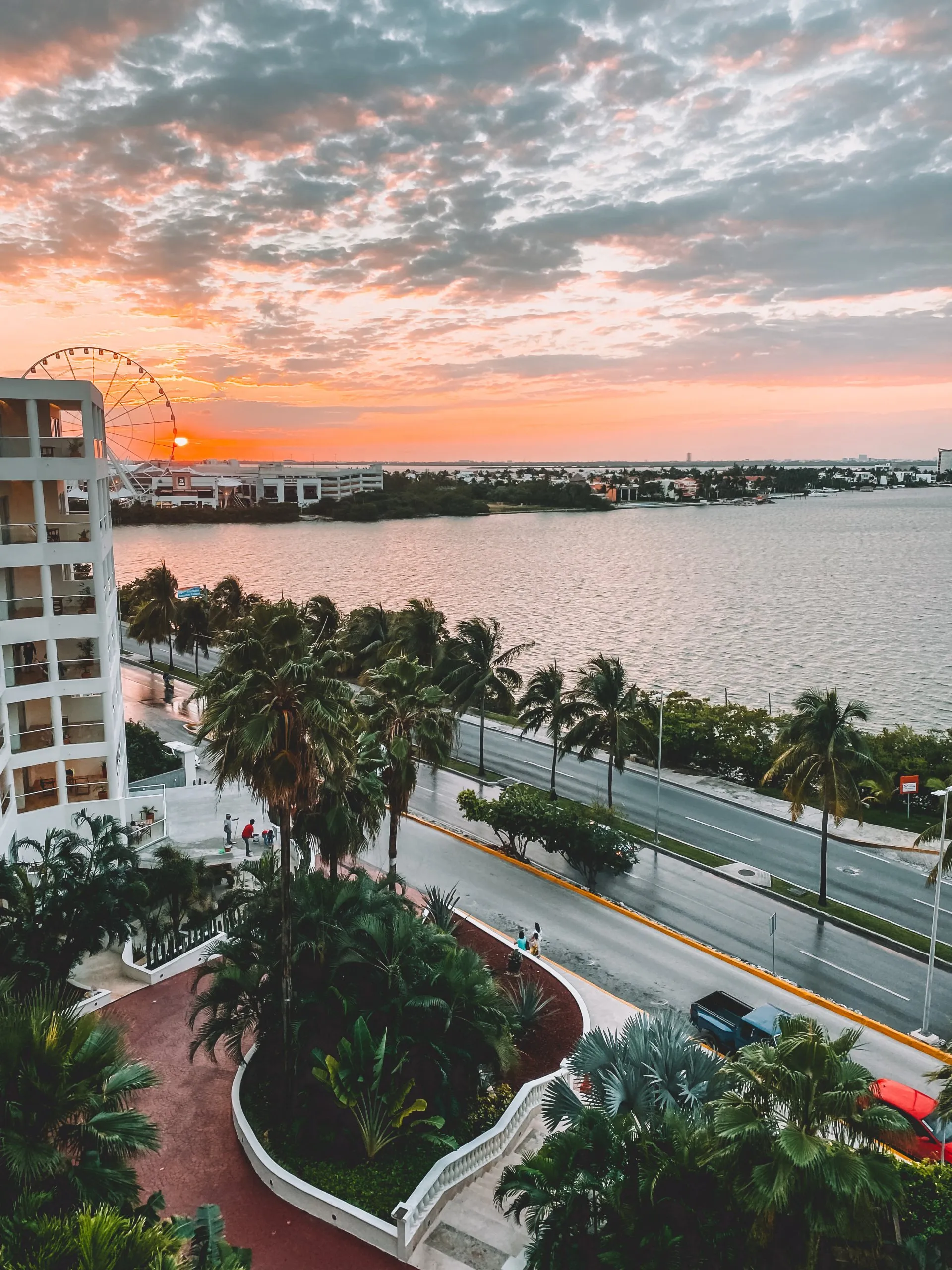 Sonnenuntergang über der Lagune von Cancún mit Ferris Wheel, Palmen und Hotelzone in Mexiko