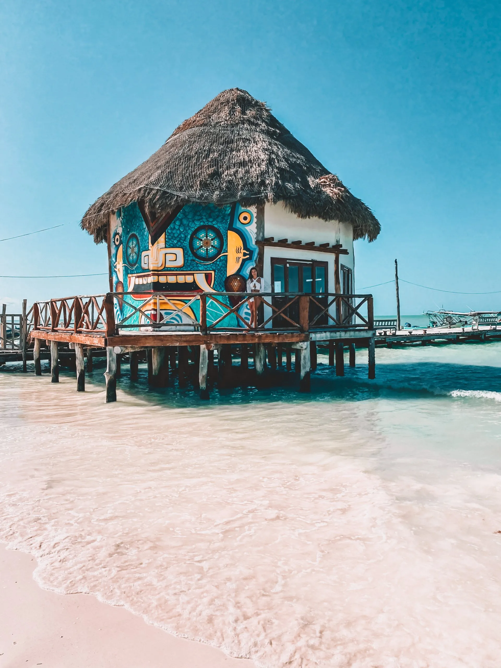 Bunte Strandhütte auf Stelzen im türkisblauen Wasser, Mexiko