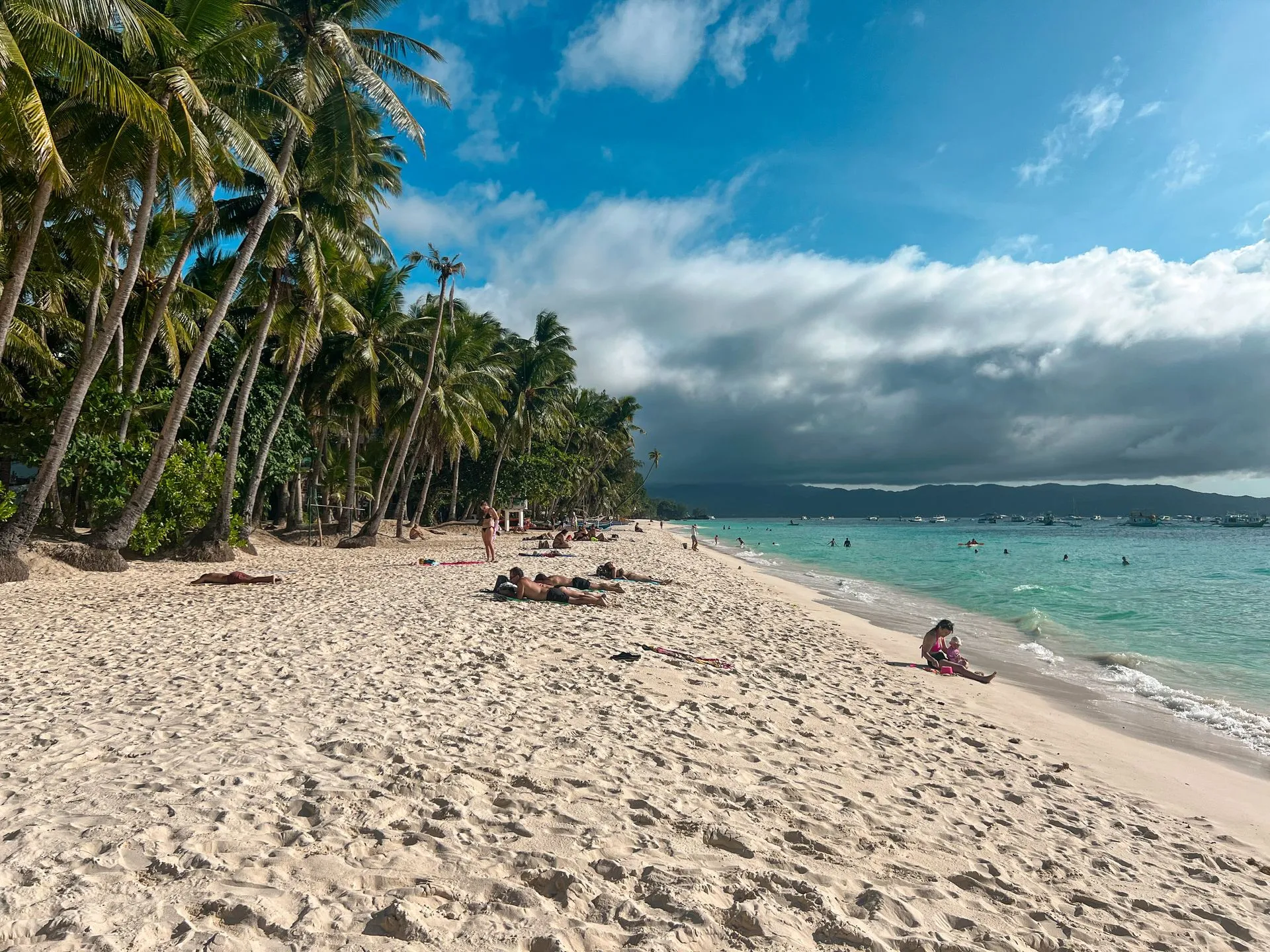 Weißer Sandstrand auf Boracay, Philippinen, mit Palmen und türkisblauem Wasser unter blauem Himmel