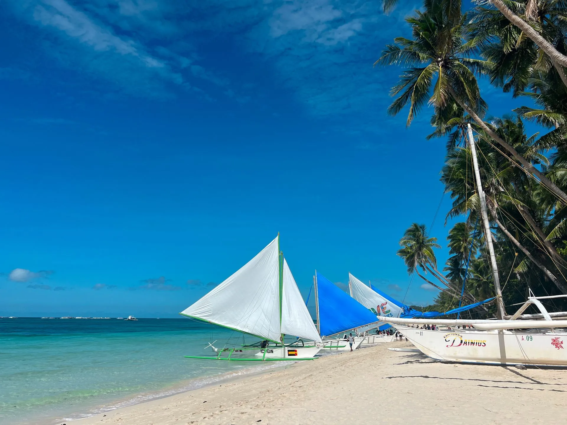 Traditionelle Paraw-Segelboote am weißen Sandstrand von Boracay mit türkisblauem Wasser, Philippinen