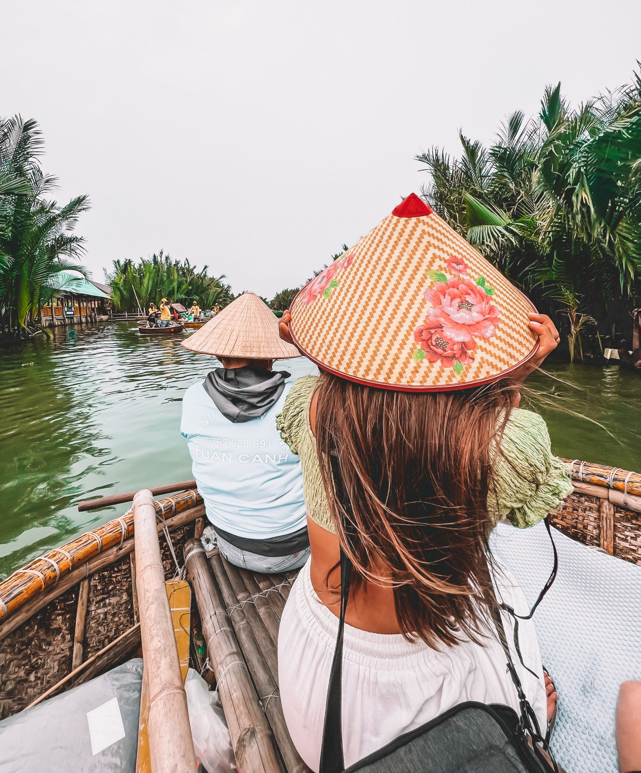 Bootsfahrt durch Kokospalmen-Wasserwald in Hoi An, Vietnam – Touristin mit traditionellem Nón-lá-Hut