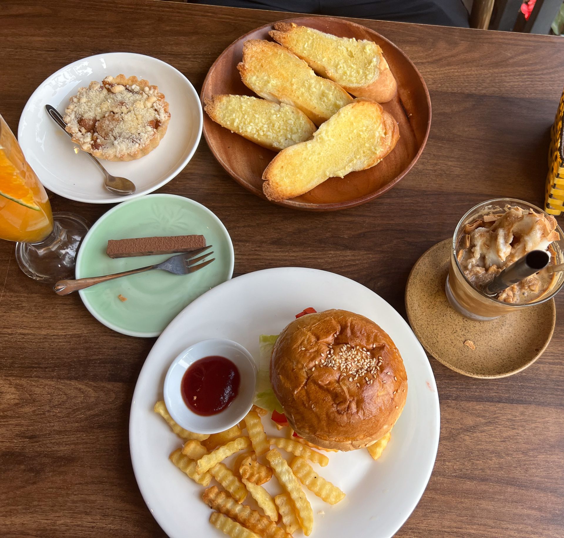 Café-Tisch in Vietnam mit Burger, Pommes, Knoblauchbrot, Kuchen und Eiskaffee – typisches Café in Hanoi