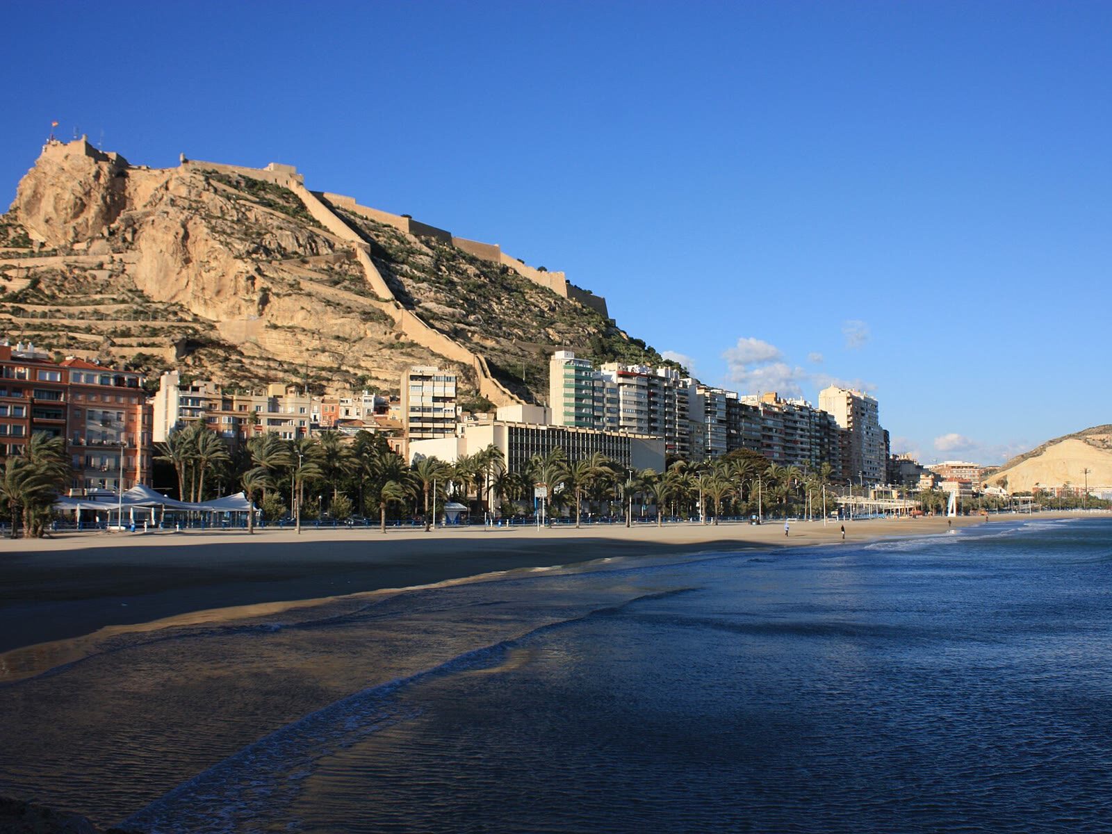 El Castillo de Santa Bárbara sobre el monte Benacantil, con la playa del Postiguet y el skyline de Alicante