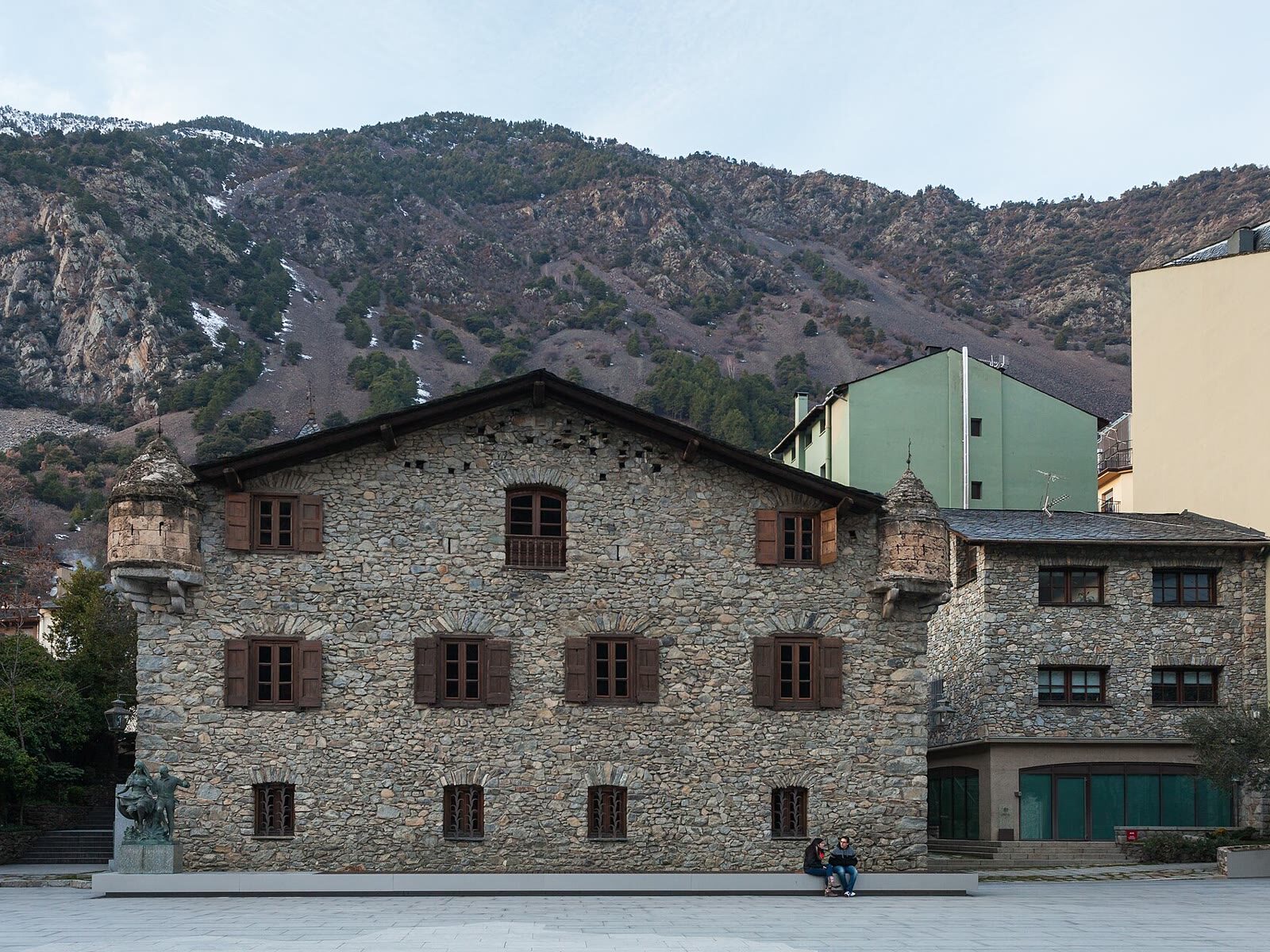 Fachada de piedra de la Casa de la Vall en Andorra la Vella, con las montañas al fondo