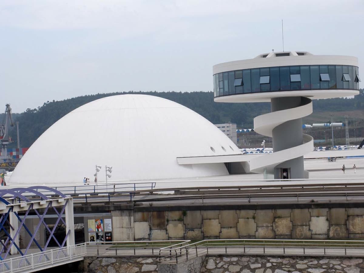 Cúpula y torre mirador del Centro Niemeyer, con las instalaciones portuarias de la ría de Avilés al fondo