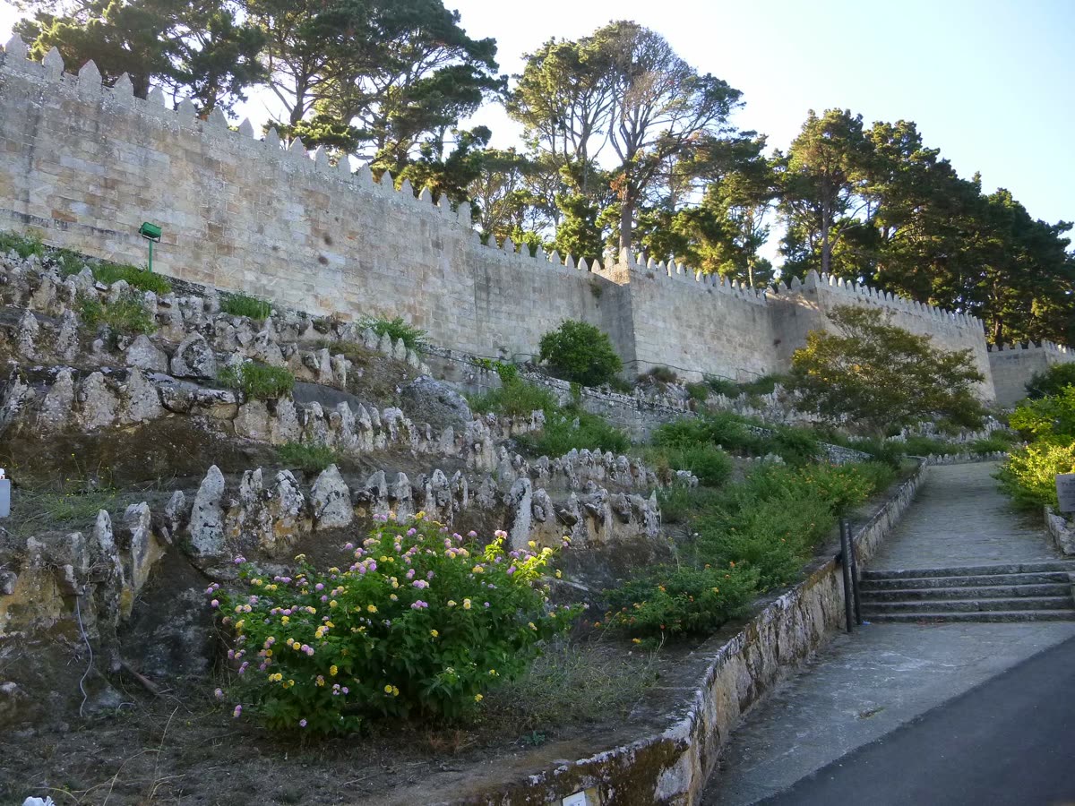 Murallas almenadas de la fortaleza de Monterreal en Baiona, entre la vegetación