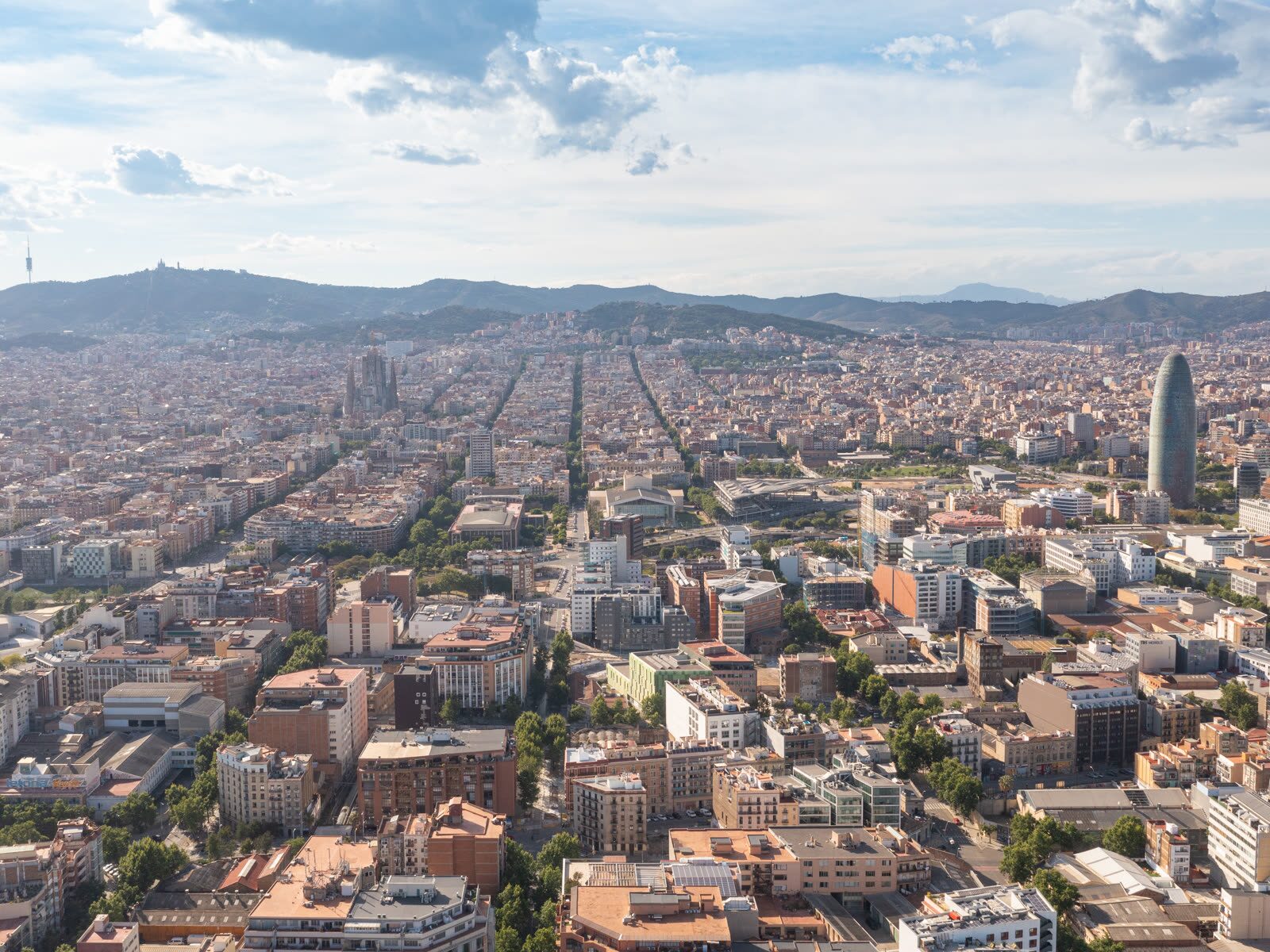Vista aérea de la Sagrada Família y la cuadrícula del Eixample en Barcelona, con la Torre Glòries al fondo
