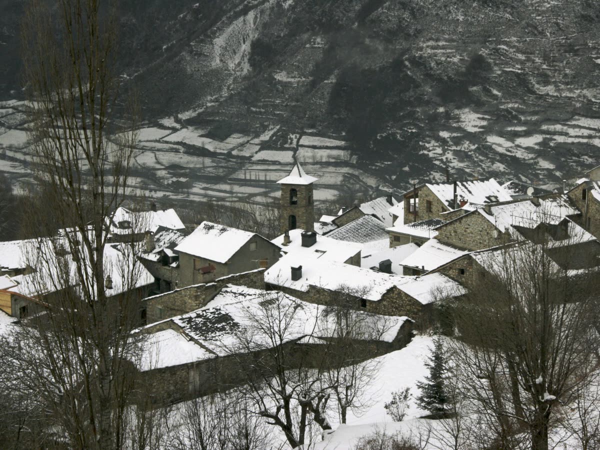 Tejados nevados y campanario de piedra del núcleo tradicional de Cerler, en el valle de Benasque
