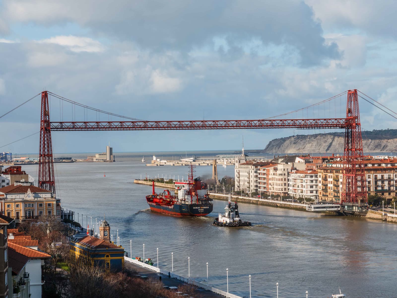 Vista del Puente Colgante de Vizcaya sobre la ría de Bilbao, con un buque de carga navegando bajo la estructura
