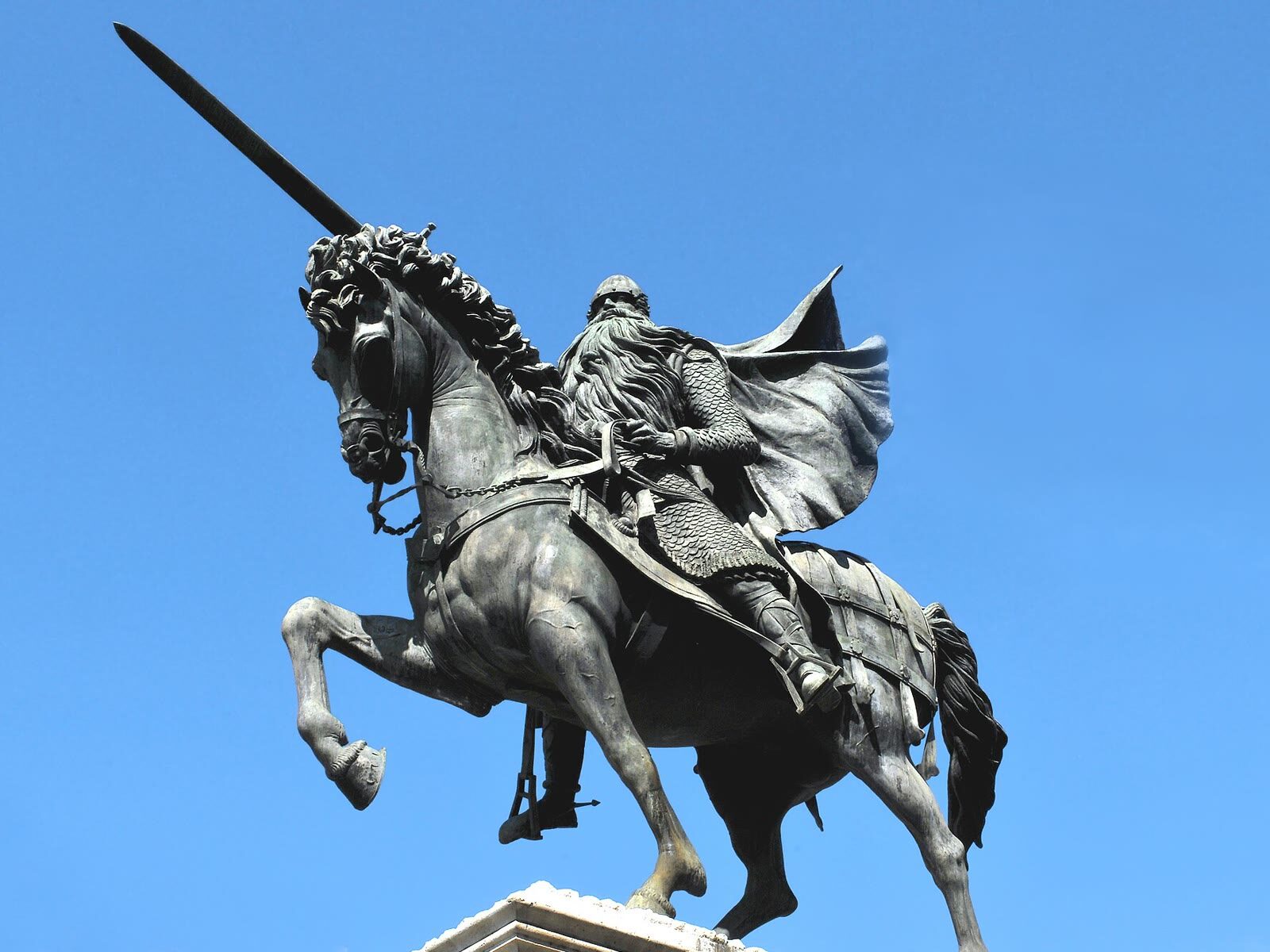 Estatua ecuestre del Cid Campeador en Burgos, con la espada en alto, contra un cielo azul despejado